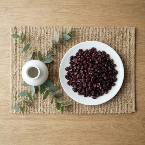 Top-down view of a plate of dried cranberries on a rustic jute mat, featuring the uniform size and nutrient-dense appearance of Oasis products.