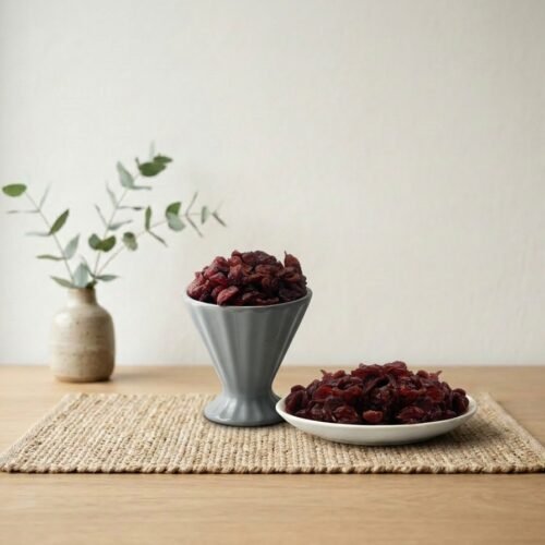 Premium dried cranberries by Oasis Dry Fruits in a grey pedestal cup and side plate, highlighting their vibrant ruby red color.