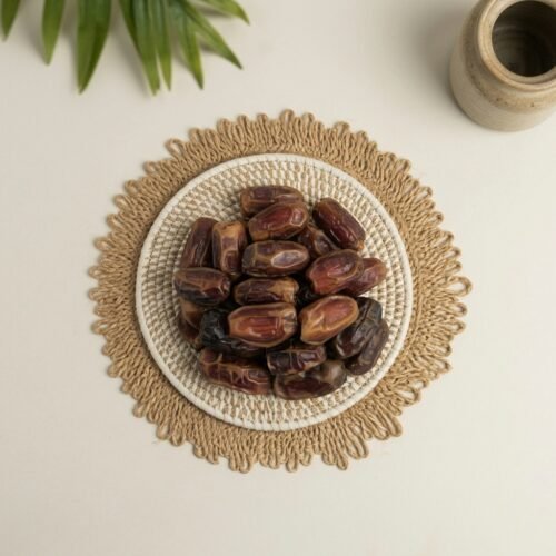 Close-up top-down shot of original Mashrook dates on a rustic mat, showcasing the glossy skin and premium quality check.