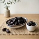 Premium blackberry plum dried by Oasis Dry Fruits in a white plate, showcasing the deep dark skin and plump, succulent texture.