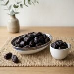 Premium blackberry plum dried by Oasis Dry Fruits in a white plate, showcasing the deep dark skin and plump, succulent texture.