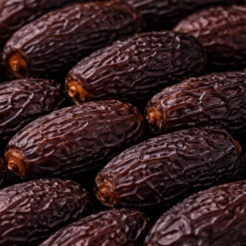 Detailed close-up of regular Kalmi dates (Safawi) showing the characteristic wrinkled skin and soft, nutrient-dense flesh.