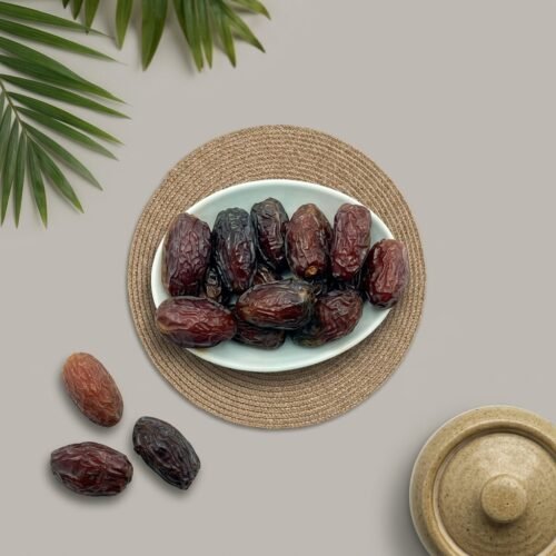 Close-up top-down shot of fresh medium Medjool dates, highlighting the glossy skin and high moisture content.