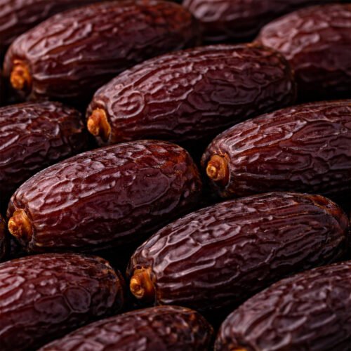 Close-up view of fresh medium Medjool dates showing soft moist flesh and natural skin.