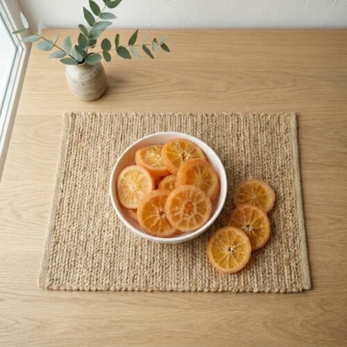 Top-down view of Oasis Dry Fruits premium dried orange slices on a rustic jute mat, showcasing the vibrant citrus color and natural round shape.