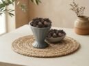 Whole smoky Black Cardamom pods served in a grey pedestal ceramic cup by Oasis Dry Fruits.