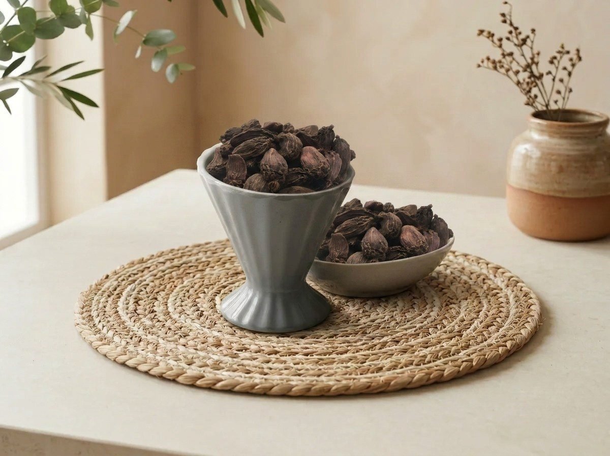 Whole smoky Black Cardamom pods served in a grey pedestal ceramic cup by Oasis Dry Fruits.