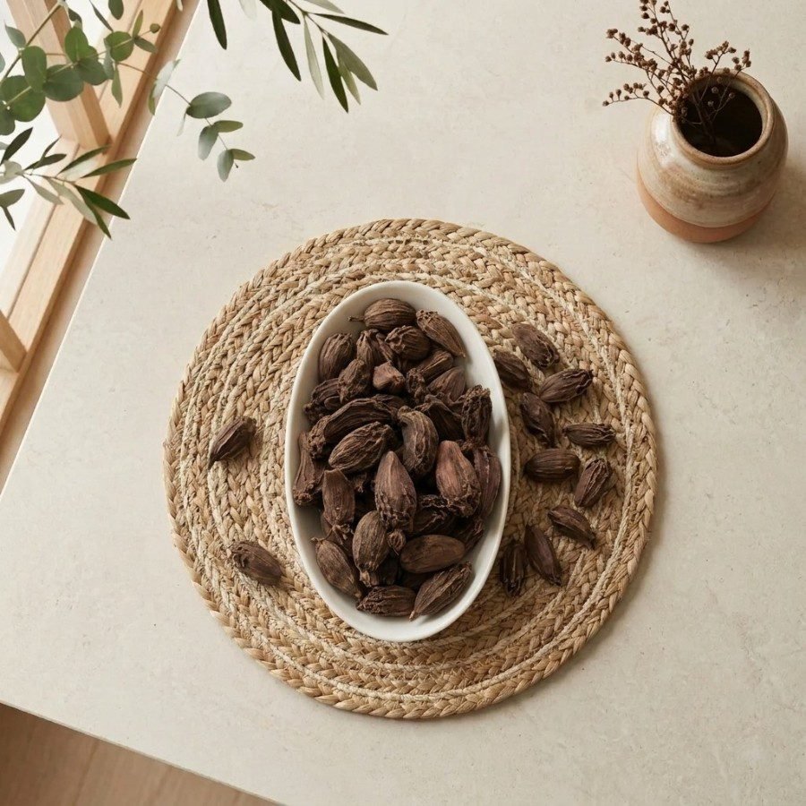 Top view flat lay of premium Black Cardamom pods in an oval dish by Oasis Dry Fruits.