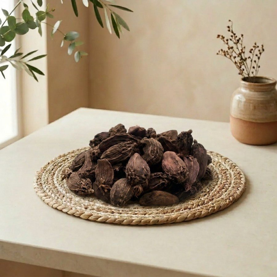 Side angle lifestyle shot of organic whole Black Cardamom pods by Oasis Dry Fruits.