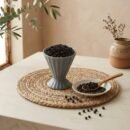 Whole aromatic Black Pepper served in a grey pedestal ceramic cup by Oasis Dry Fruits.