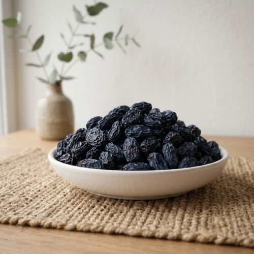 Organic black raisins with seeds served in a ceramic bowl by Oasis Dry Fruits.
