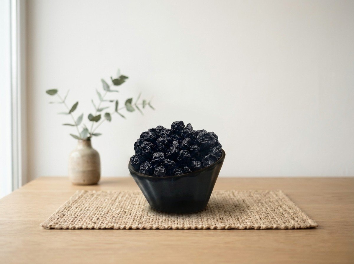 Side angle lifestyle shot of blue berry dried in a dark bowl by Oasis Dry Fruits.