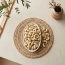 Top view flat lay of raw cashews king size in an oval dish by Oasis Dry Fruits.