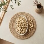 Top view flat lay of raw cashews king size in an oval dish by Oasis Dry Fruits.