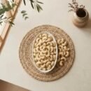 Top view flat lay of raw cashews premium large in an oval dish by Oasis Dry Fruits.