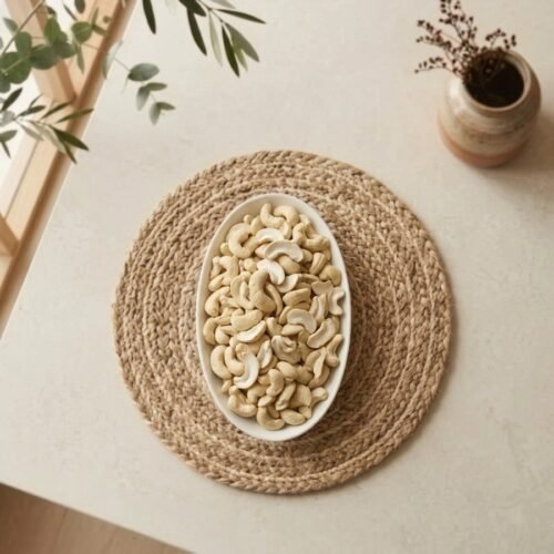 Top view flat lay of raw cashews splits in an oval white dish by Oasis Dry Fruits.