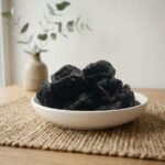 Premium organic dried prunes served in a white ceramic bowl by Oasis Dry Fruits.