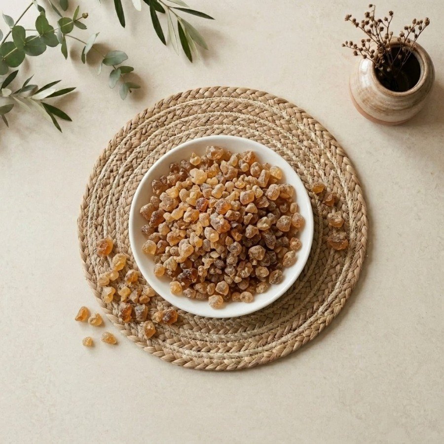 Top view flat lay of premium Gond edible gum crystals in a white bowl by Oasis Dry Fruits.