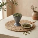 Whole Green Cardamom 8mm pods served in a grey pedestal ceramic cup by Oasis Dry Fruits.