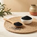 Side angle lifestyle view of black kalonji seeds in bowl and spoon by Oasis Dry Fruits.
