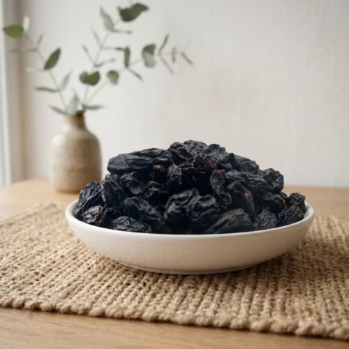Large Black Raisins Without Seeds served in a white ceramic bowl by Oasis Dry Fruits.