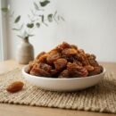 Premium organic Munakka served in a white ceramic bowl by Oasis Dry Fruits.