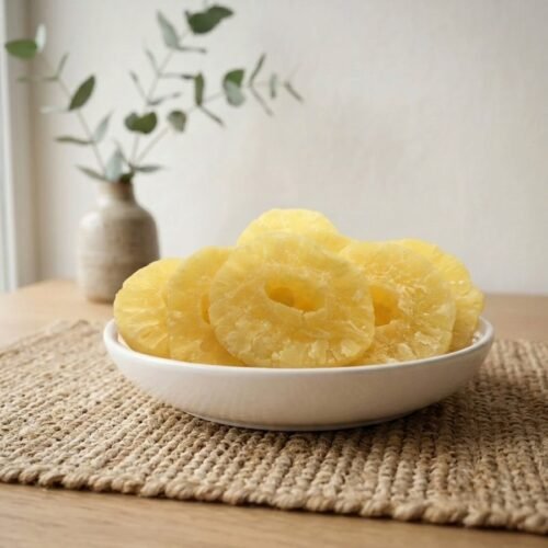 Side angle lifestyle shot of sweet Pineapple (Dried) rings in a white bowl by Oasis Dry Fruits.