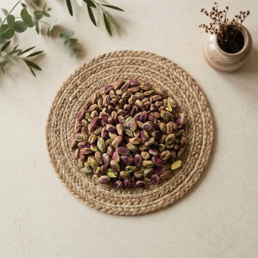 Top view flat lay of raw pista kernels iran on a woven mat by Oasis Dry Fruits.