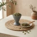 Raw organic pumpkin seeds filled in a grey ceramic cup by Oasis Dry Fruits.