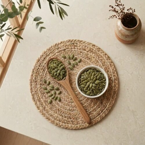Top view flat lay of raw pumpkin seeds in a white bowl with wooden spoon by Oasis Dry Fruits.