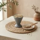 Raw shelled watermelon seeds filled in a grey ceramic cup by Oasis Dry Fruits.