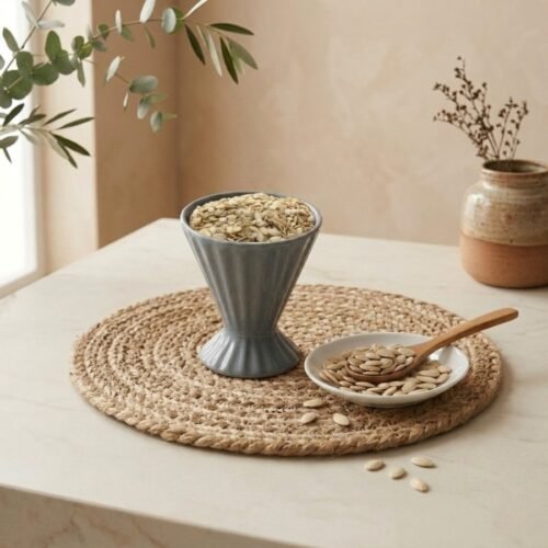Raw shelled watermelon seeds filled in a grey ceramic cup by Oasis Dry Fruits.