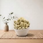 Side angle lifestyle shot of crunchy Flavoured Cashew (Salted) in a white bowl by Oasis Dry Fruits.