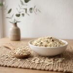 Side angle lifestyle shot of organic Oats Flakes in a white bowl and wooden spoon by Oasis Dry Fruits.