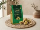 Cocoa Melts Pistachio 100g pouch with pistachio-crusted wafer rolls on a jute mat