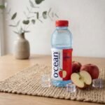 Ocean Fruit Drink Apple chilled bottle with fresh red apples and ice cubes