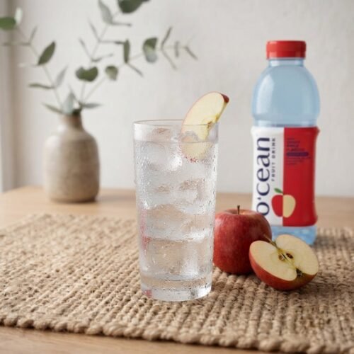 Glass of Ocean Fruit Drink Apple with ice and apple slice, bottle behind