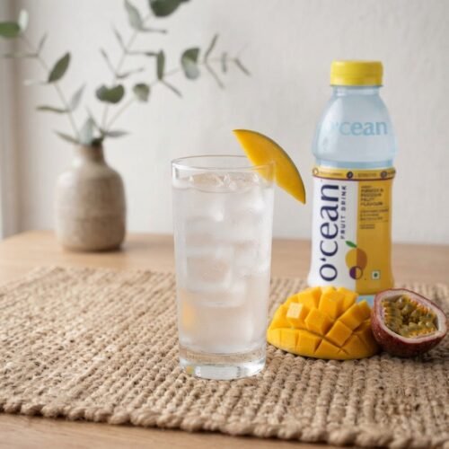 Glass of Ocean Fruit Drink Mango and Passion Fruit with ice, bottle behind