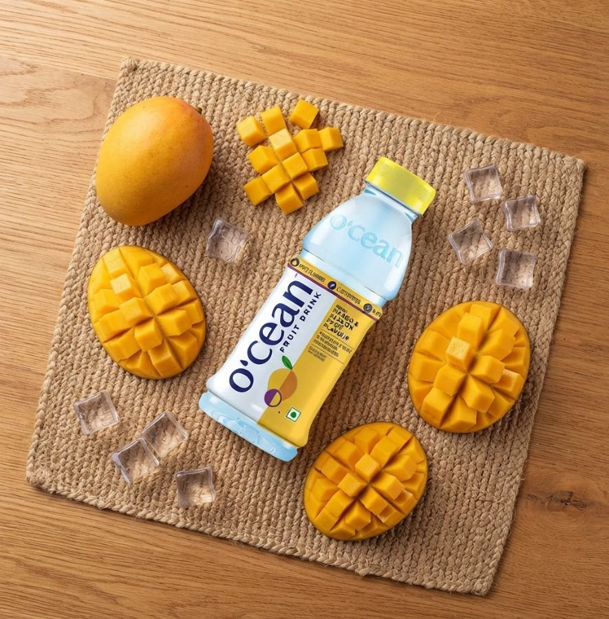 Top view of Ocean Fruit Drink Mango bottle with cut mango and ice cubes