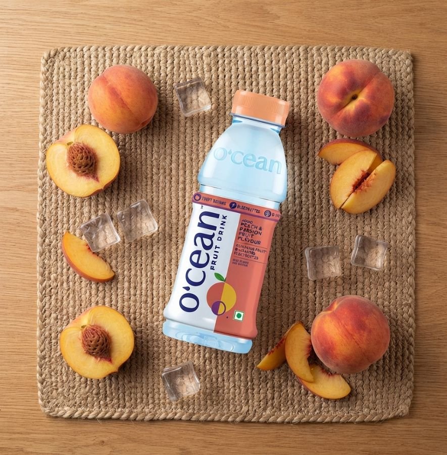 Top view of Ocean Fruit Drink Peach bottle with fresh peaches and ice cubes